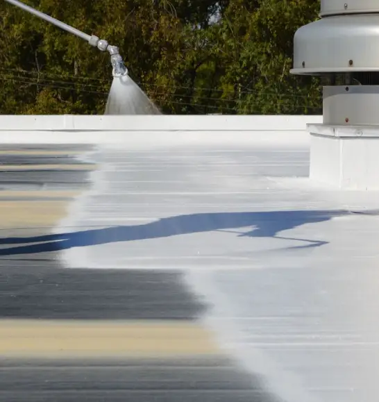 Crew applying commercial spray foam roofing system on a large flat roof in Illinois